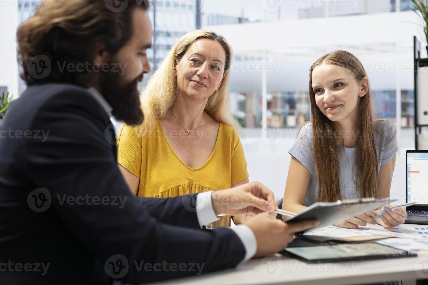 Financial advisor creating reports on investment performance, showing them to mother and daughter. Agent in office presenting portfolio economic evolution to family members photo