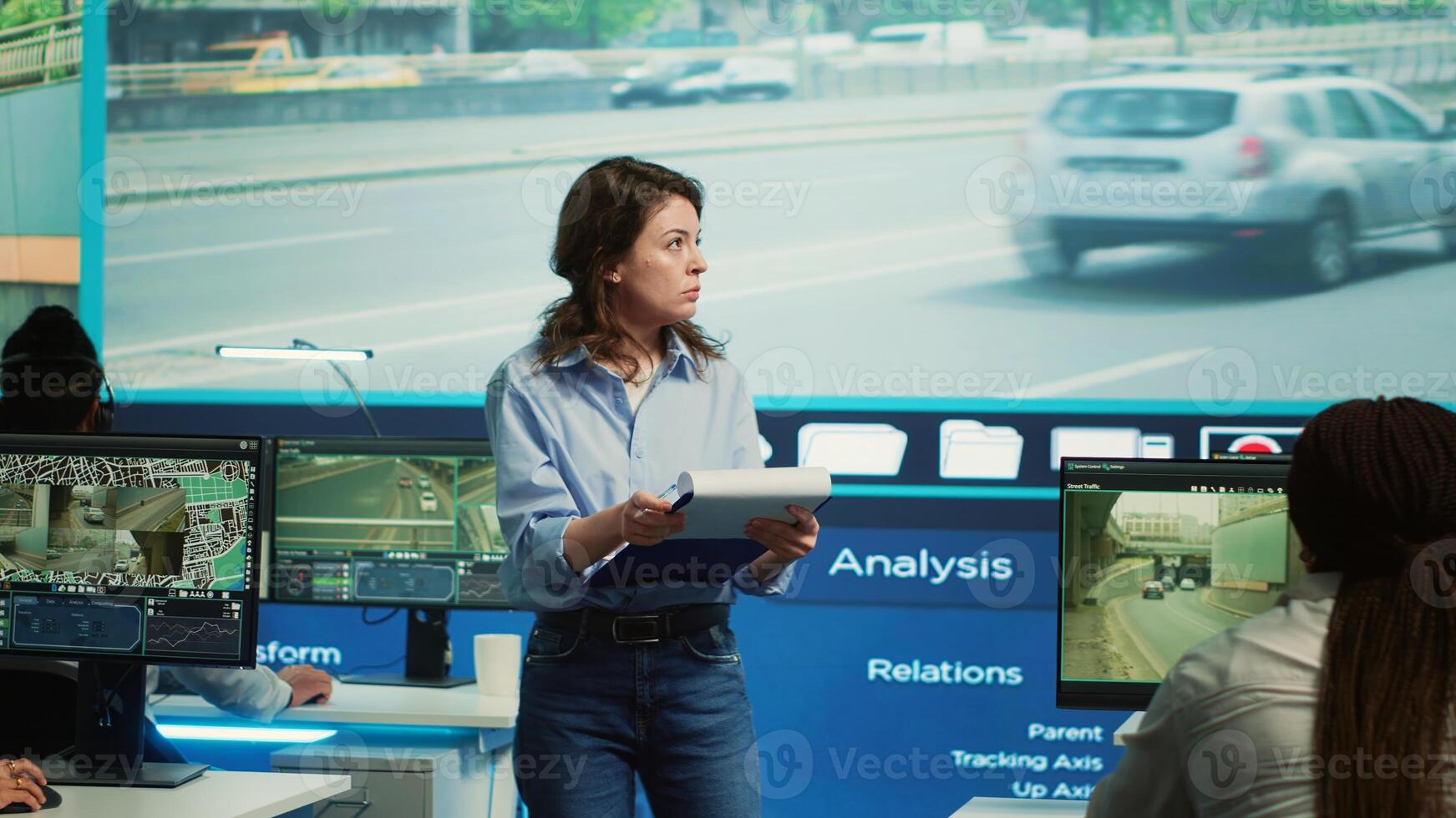 Manager overseeing employees in monitoring traffic activity, operating through surveillance footage on CCTV cameras. Diverse team work with satellite system in control center. Camera A. photo