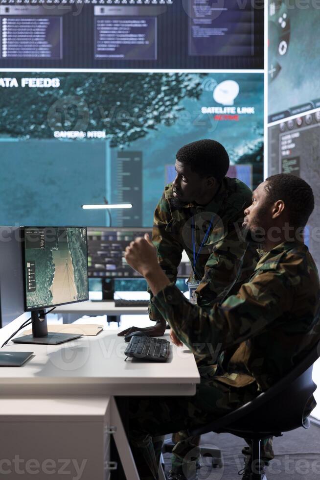 Team of army experts in a command post power base monitors satellite footage, collecting real time data and transmitting important details for a n operational success. Help with decision making. photo