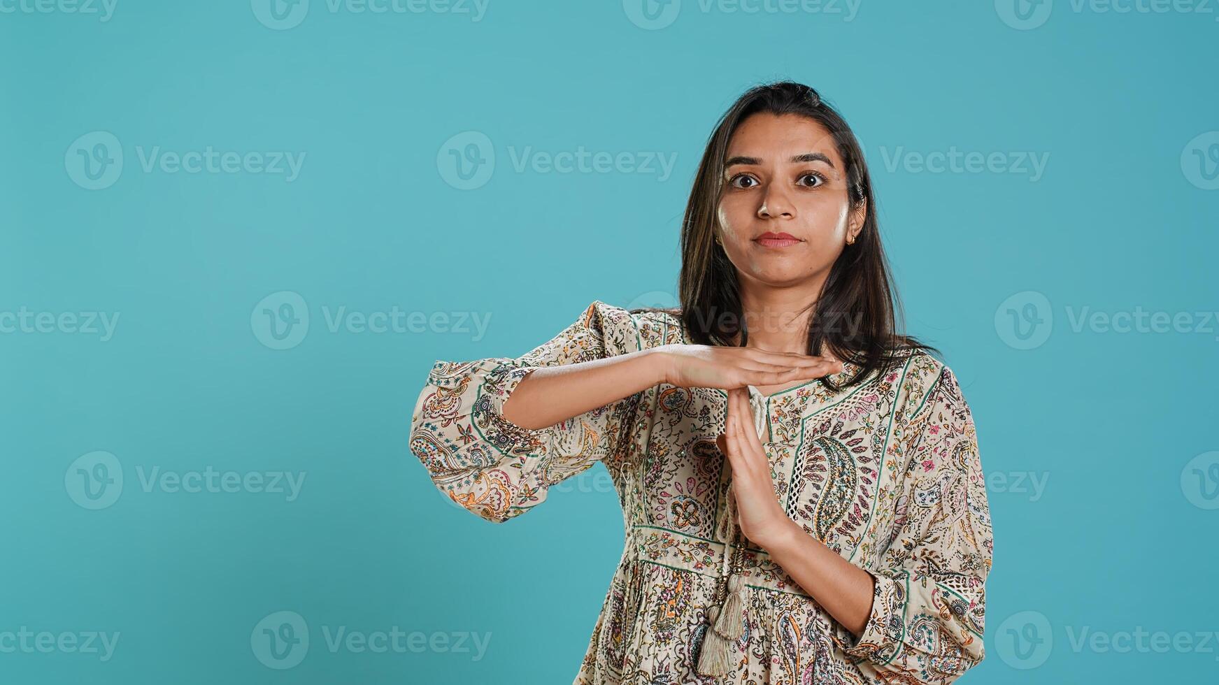 Portrait of assertive indian woman asking for timeout, doing hand gestures, feeling fatigued. Firm person doing vehement pause sign gesturing, wishing for break, studio background, camera A photo