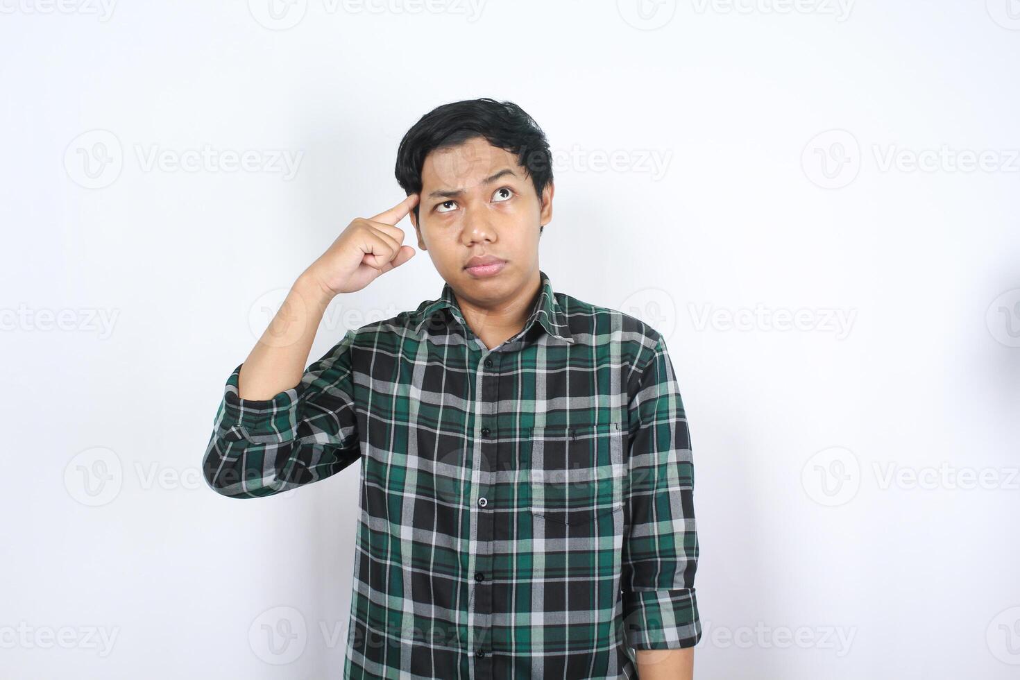 confused asian young man thoucing his head with finger showing try to remember gesture isolated photo