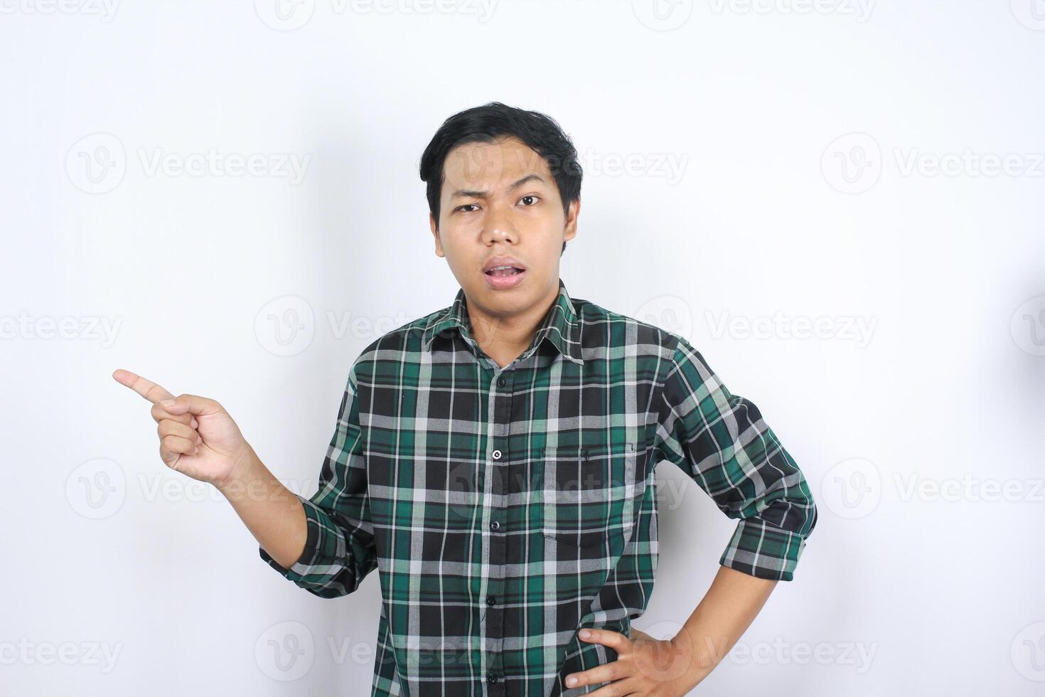 isolated attractive asian young man pointing beside to empty space with confused face and doubtful expression photo