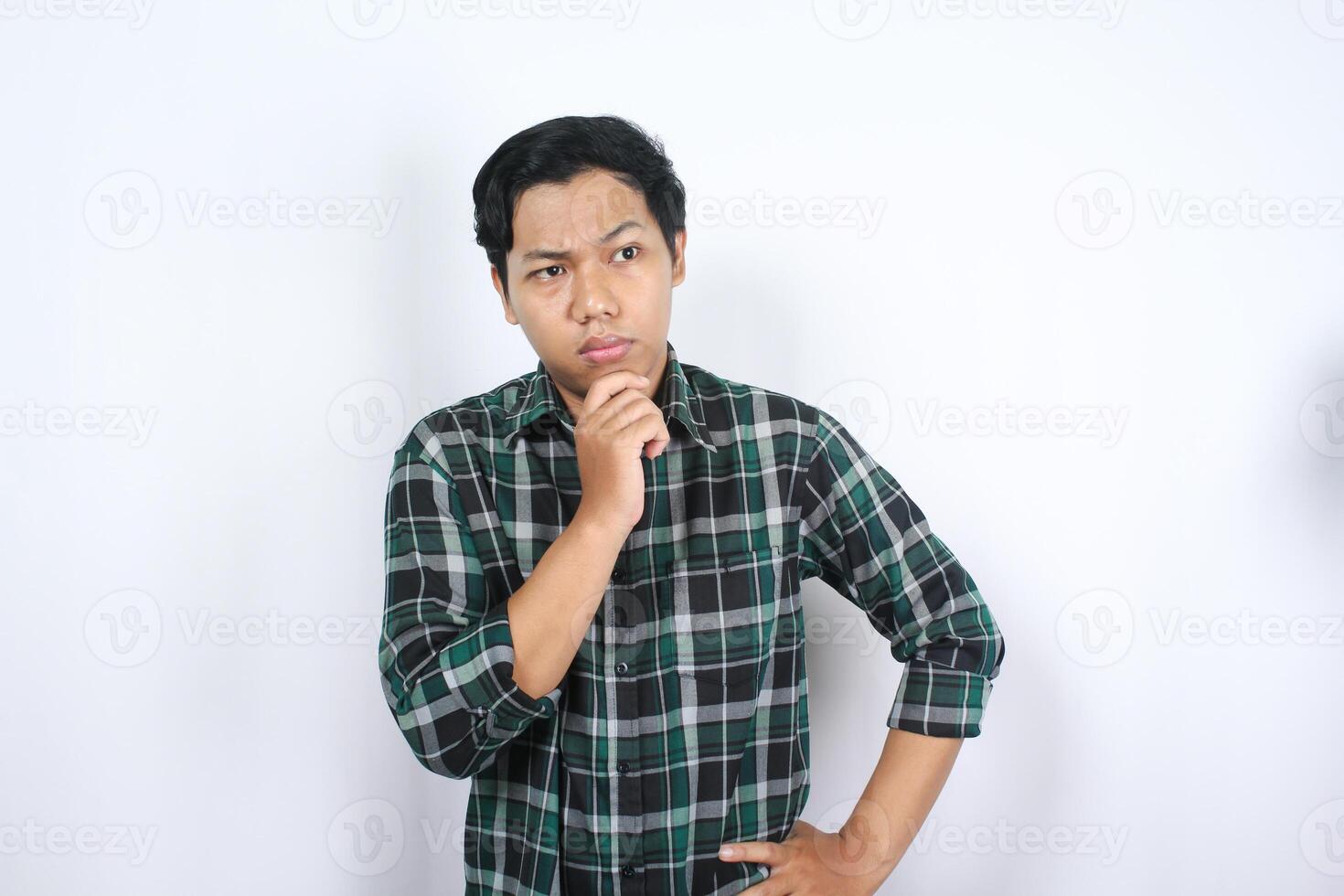 thoughtful smart asian young man wearing casual clothes making decision with hand on chin isolated photo