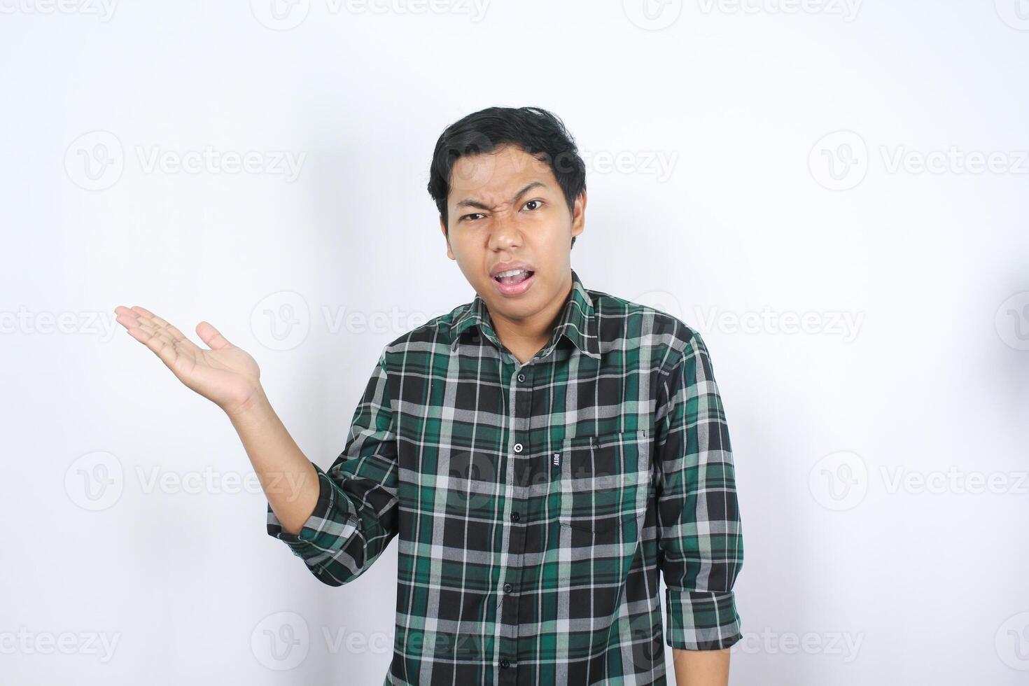 confused asian young man presenting to copy space looking at camera show shock and clueless face isolated on white background photo