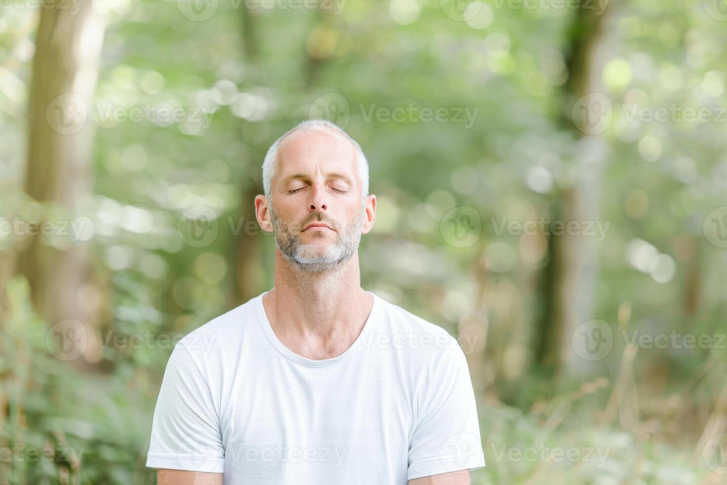 Mature Man Enjoying Peaceful Moment Meditating in Forest photo