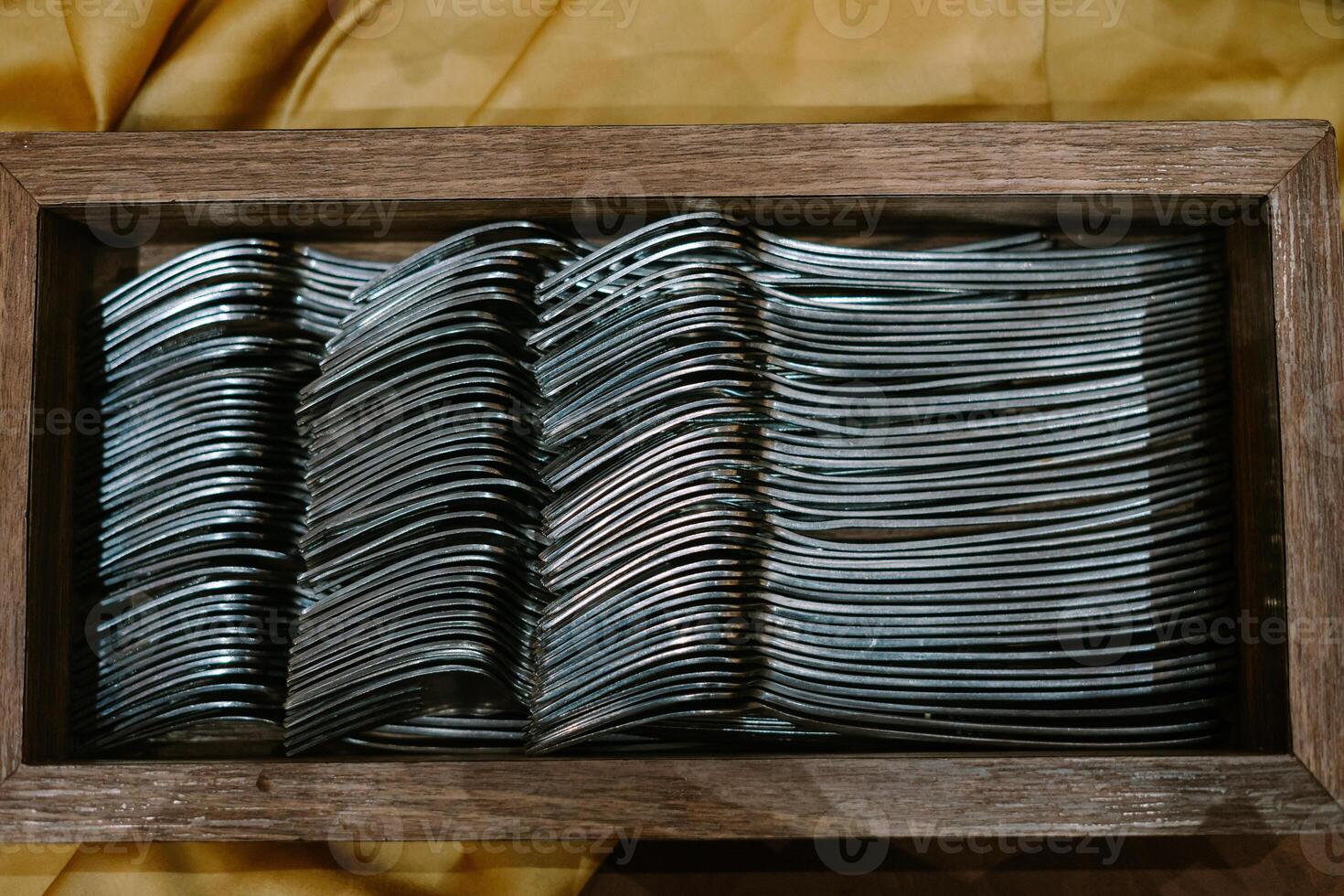 Dozens of silver forks neatly arranged in a rustic wooden holder, ready for dining or display. photo