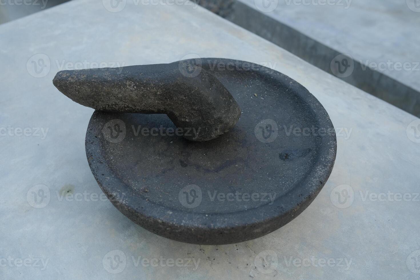 A close-up of a round stone mortar and pestle. photo