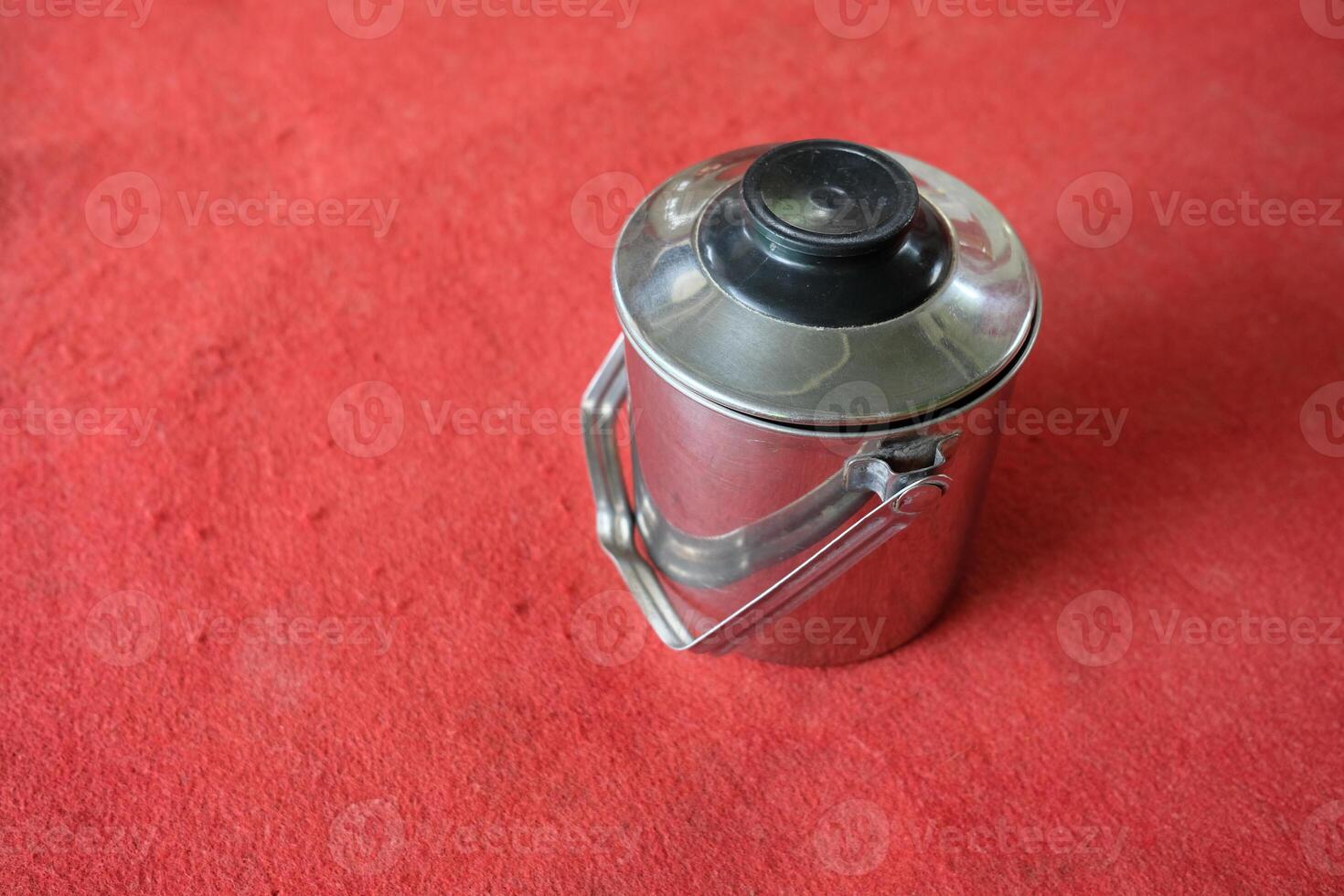 Silver thermos on red fabric background. photo