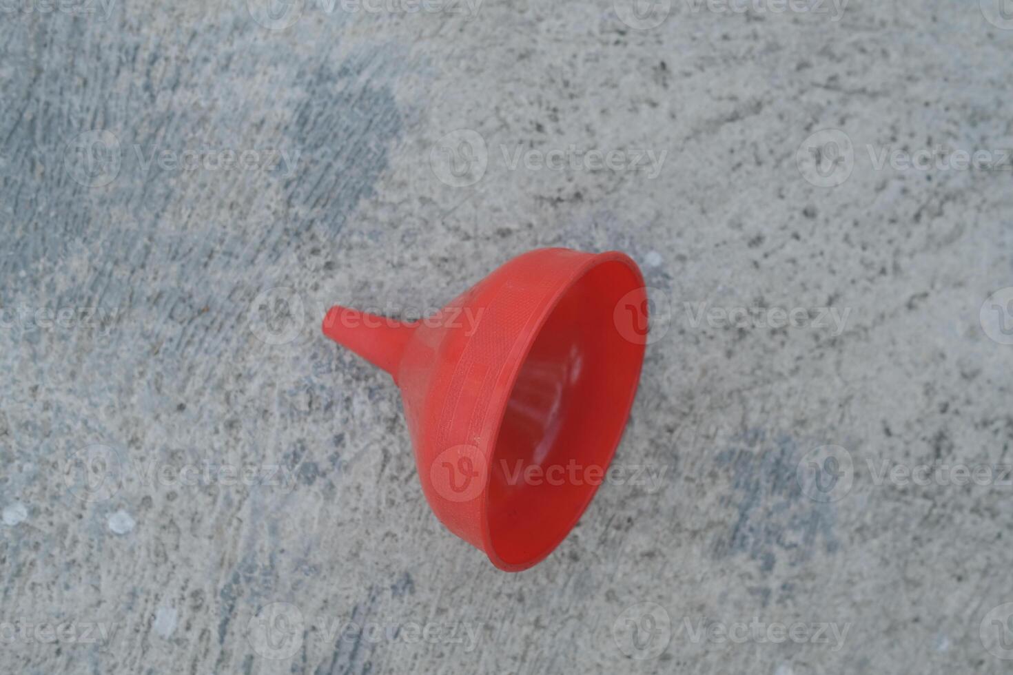 Red plastic funnel on a concrete surface. photo