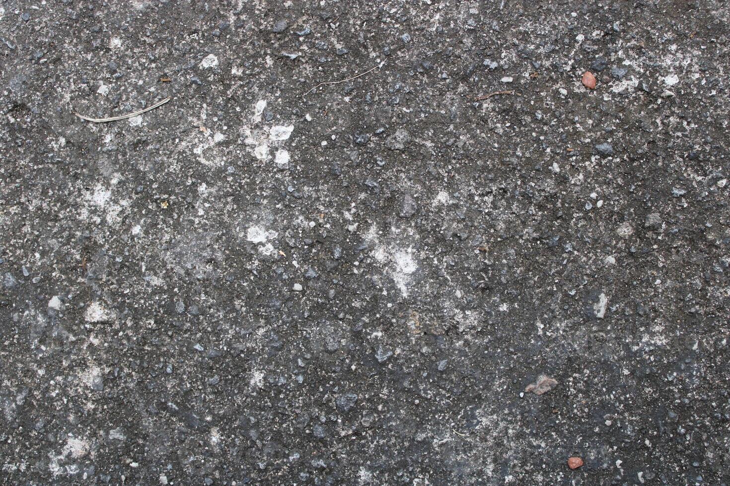 Closeup of rough, textured concrete surface with small stones and white patches. photo
