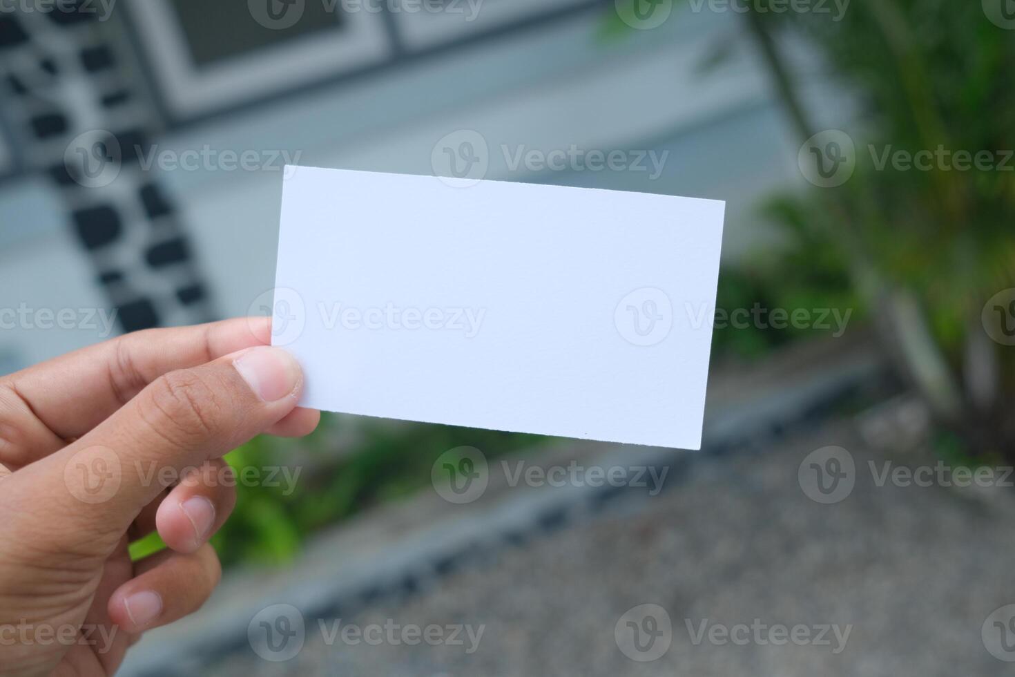 Hand holding blank white card, outdoor background. photo