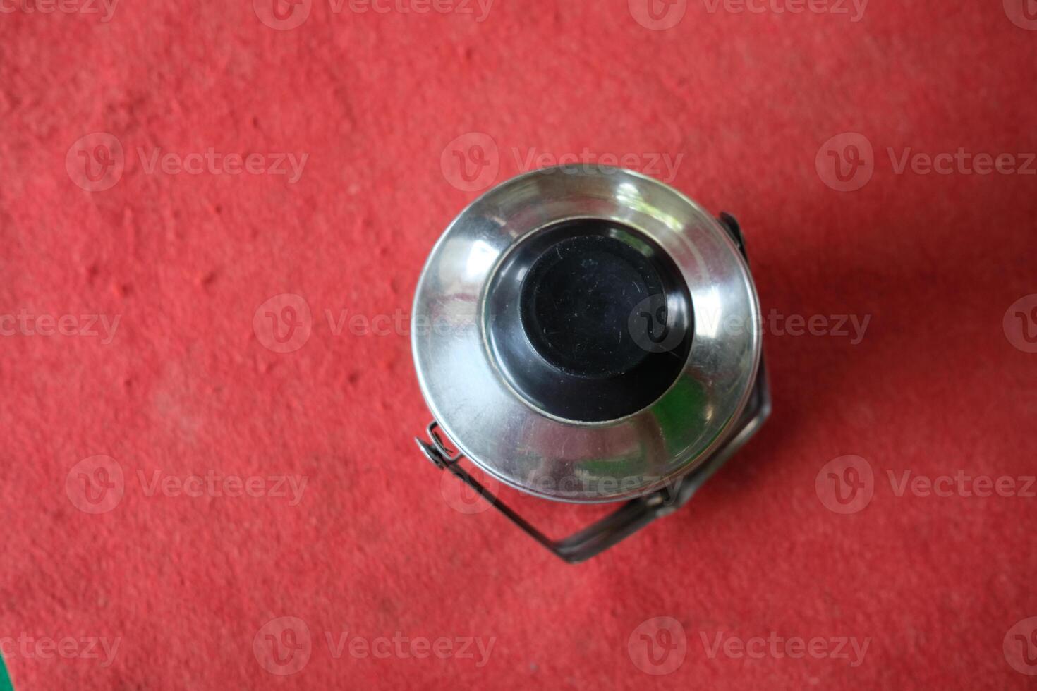 Top view of a silver metal lunch box on red textured surface. photo