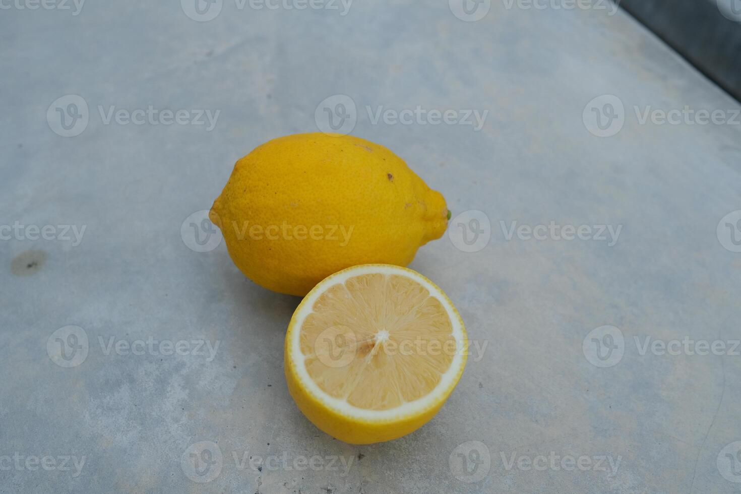 A whole lemon and a slice on a grey surface. photo
