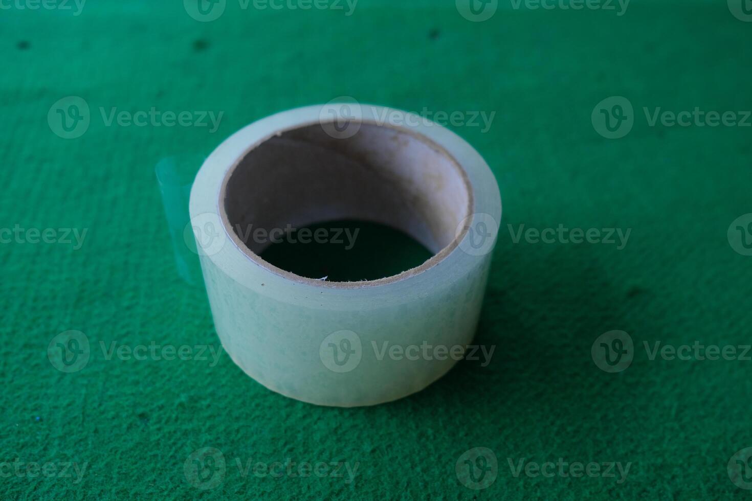 Roll of transparent tape on a green surface. photo