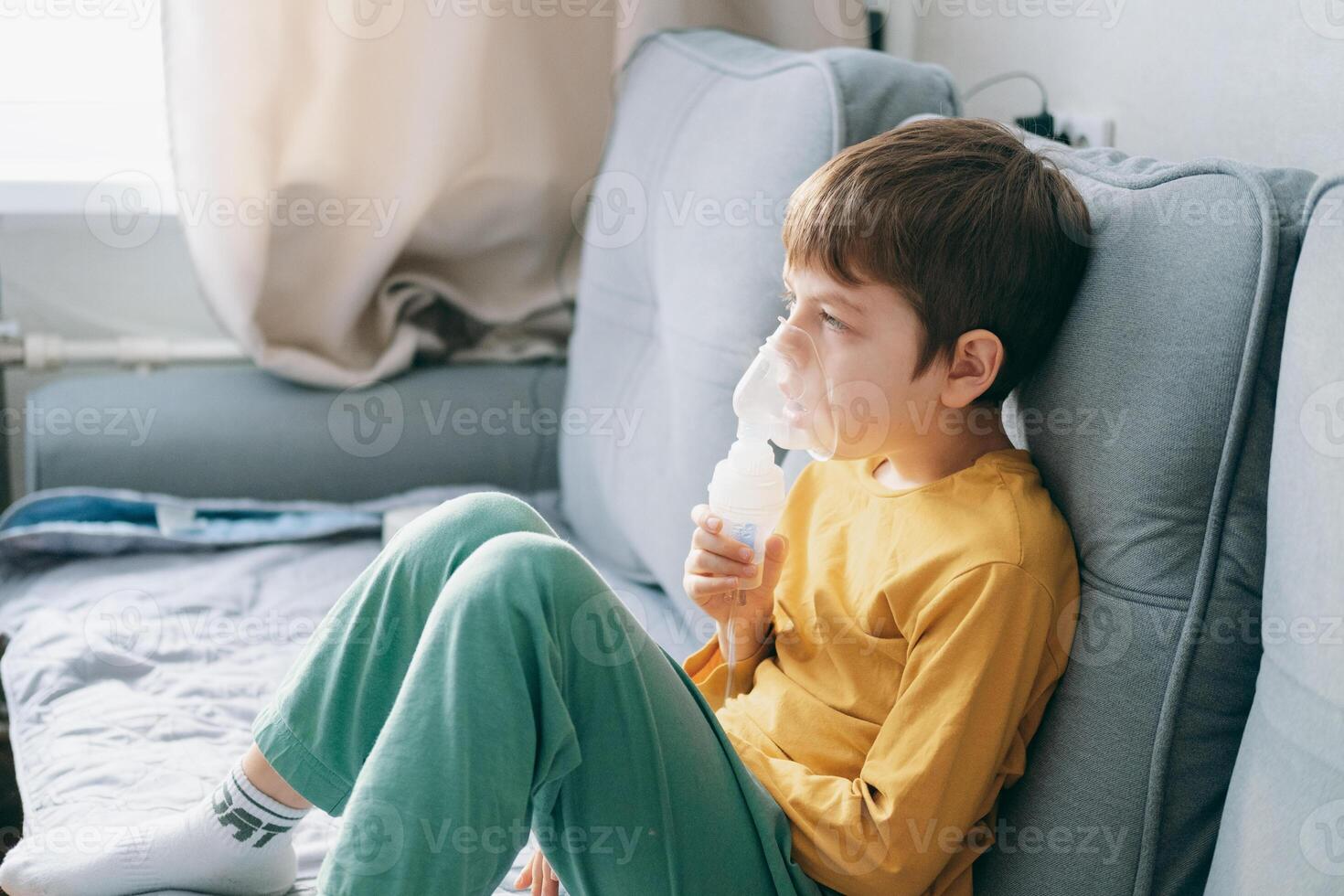little boy sits with an inhalation mask during cough and bronchitis. Treatment with an inhaler at home photo