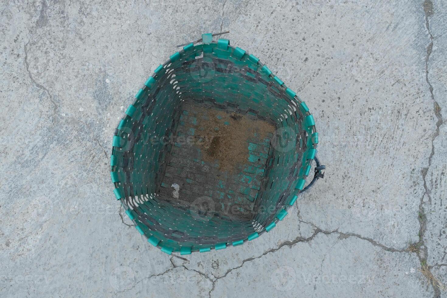 Top view of an empty green woven basket on a cracked concrete surface. photo