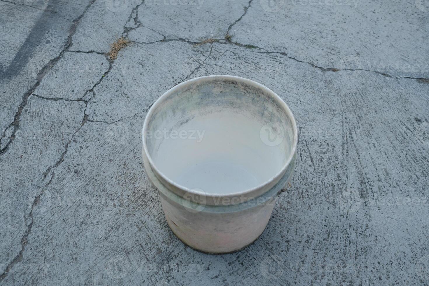 Empty white bucket on a cracked concrete surface. photo