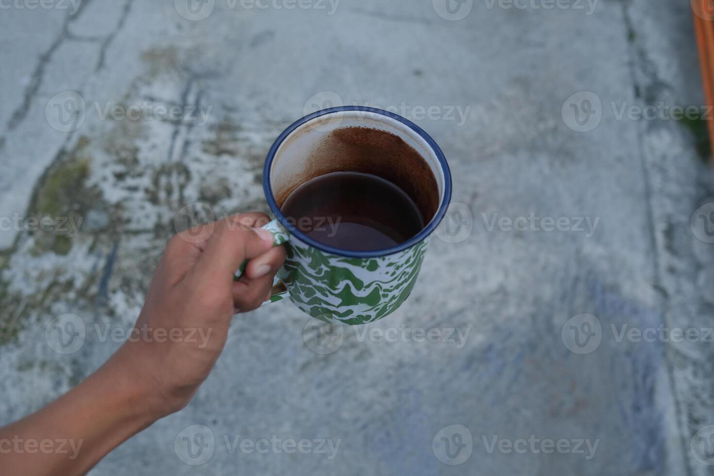 Hand holding a green patterned mug with coffee. photo