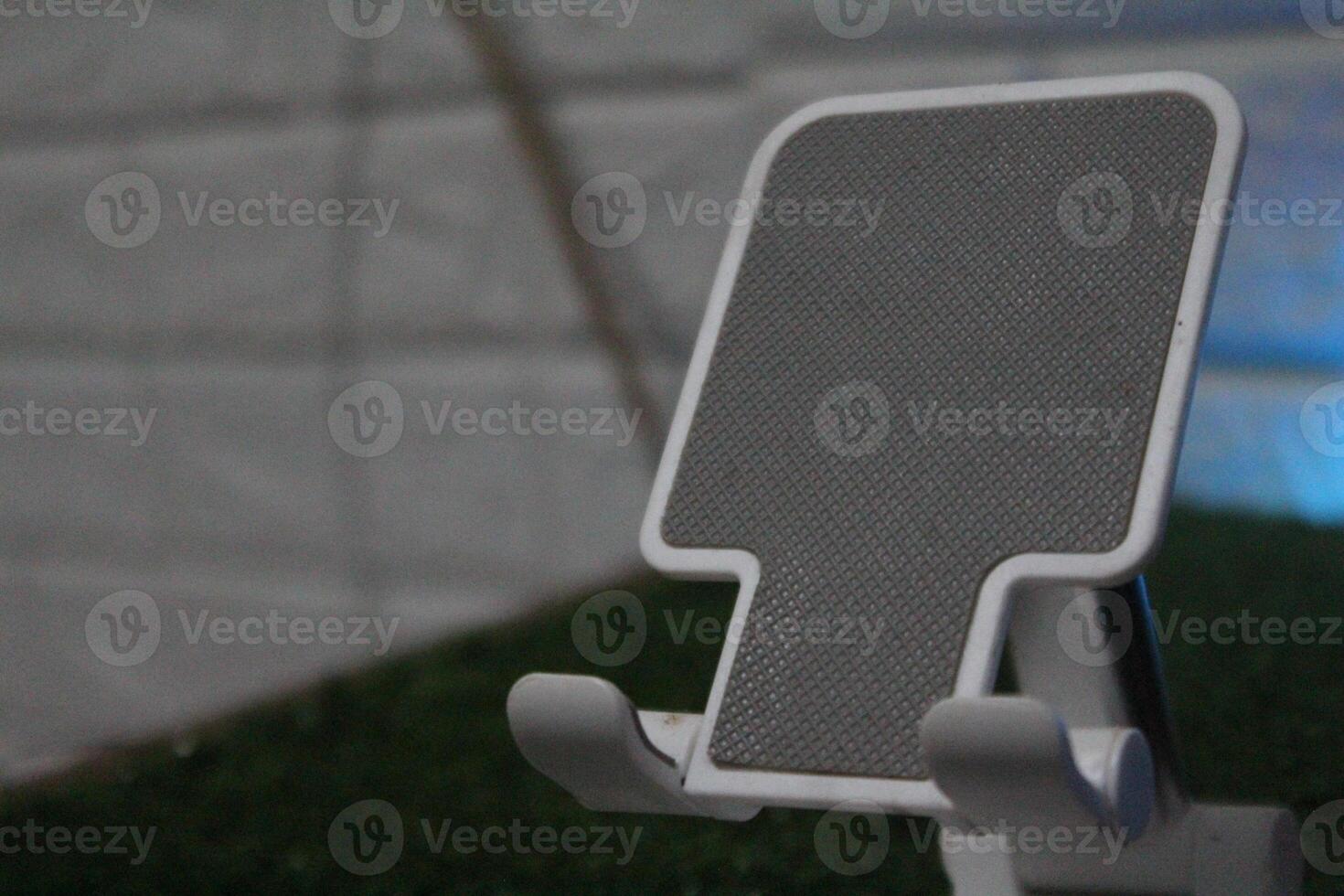 A close-up of a white phone stand with a gray, textured surface. photo