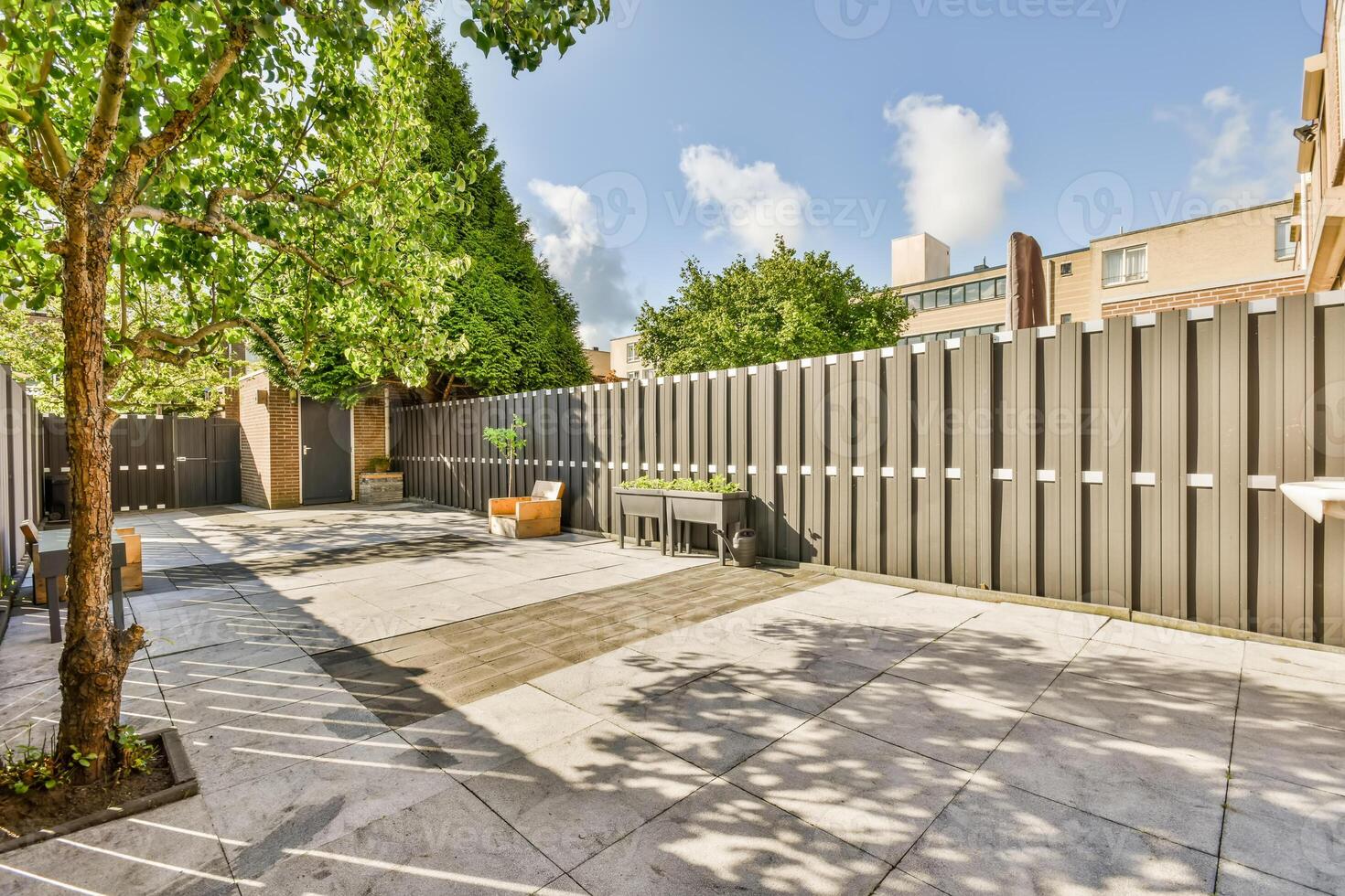 A patio with a tree and a fence photo