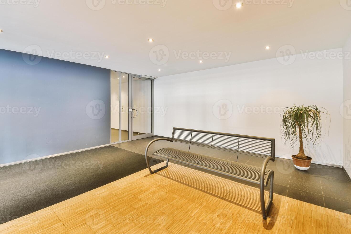 An empty office with a bench and a plant photo