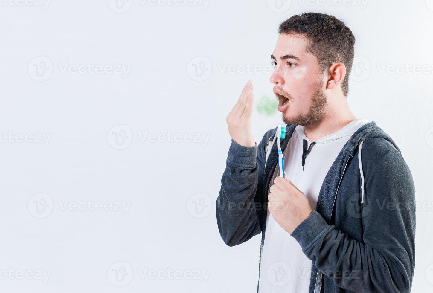 Person holding brush with bad breath problem isolated. Man holding brush checking bad breath photo