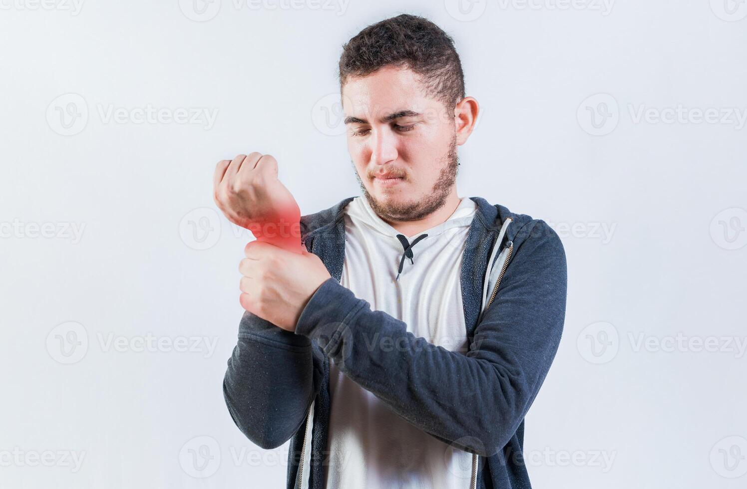 Suffering young man with pain in hand joints isolated. Person with arthritis pain rubbing hand photo