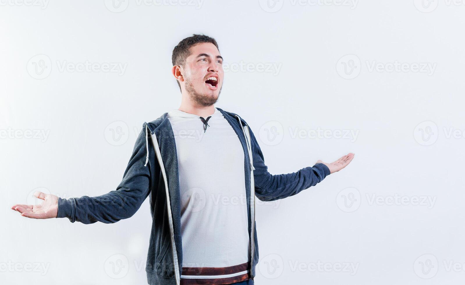 Angry young man shouting up with open hands isolated. Annoyed guy with open arms shouting isolated photo
