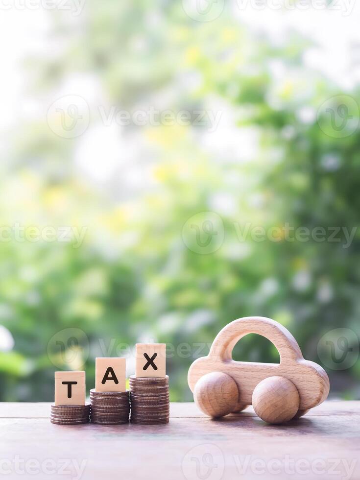 Wooden toy car and wooden blocks with the word TAX on stack of coins. The concept of saving and manage money to success transportation, Paying tax and car loan photo