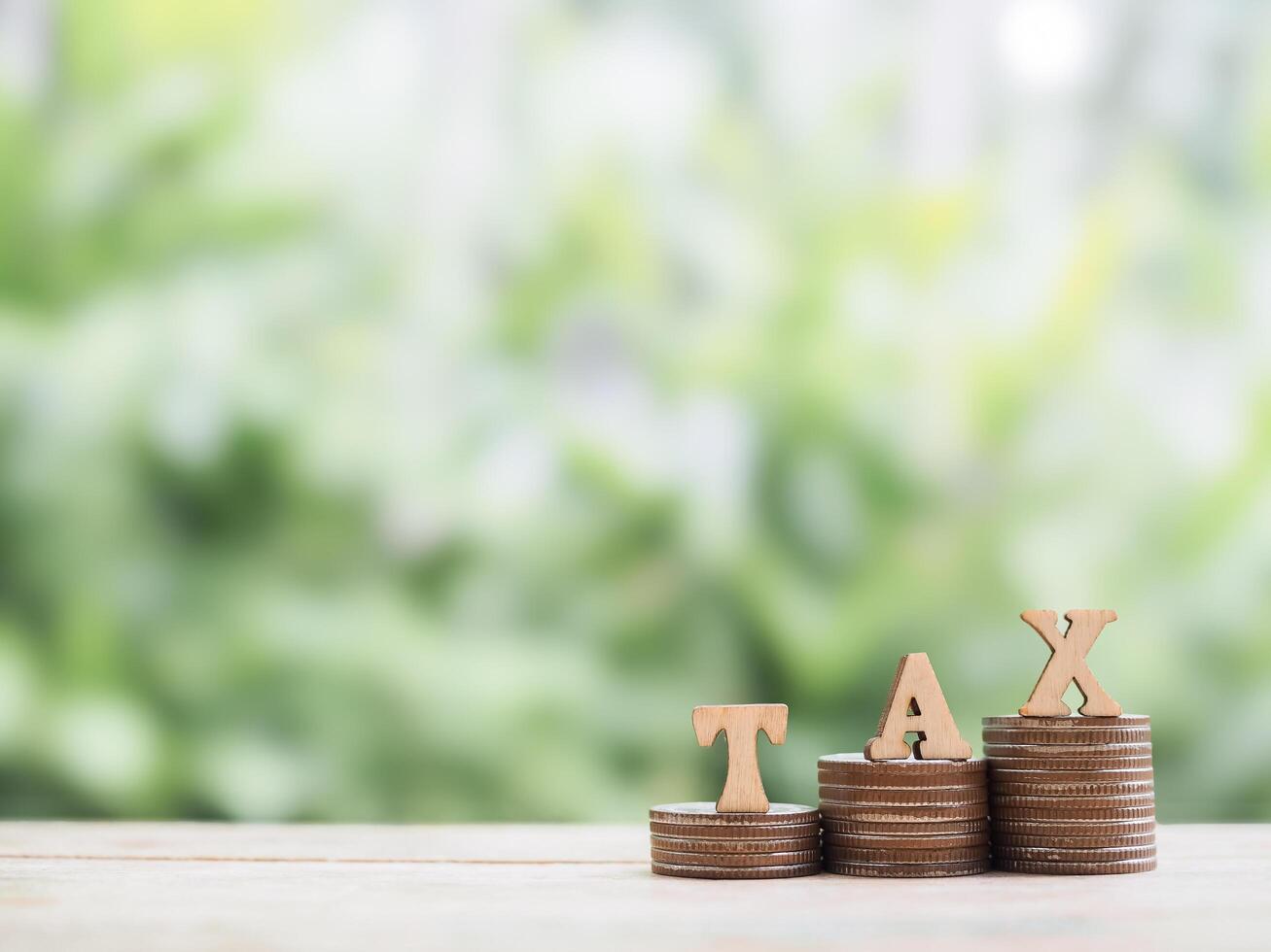 Wooden blocks with the word TAX on stack of coins. The concept of saving money for payment tax in future photo