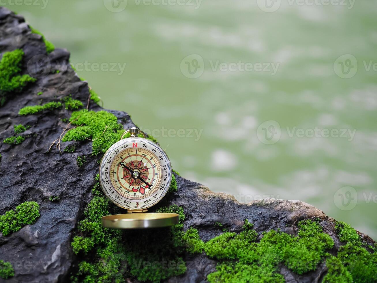 Compass on the rock with green moss background. The concept of world tourism day, Searching the right directions and Travel photo