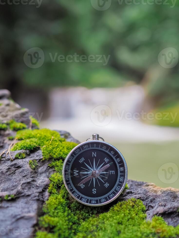 Compass on the rock with waterfall as background. The concept of world tourism day, Searching the right directions and Travel photo