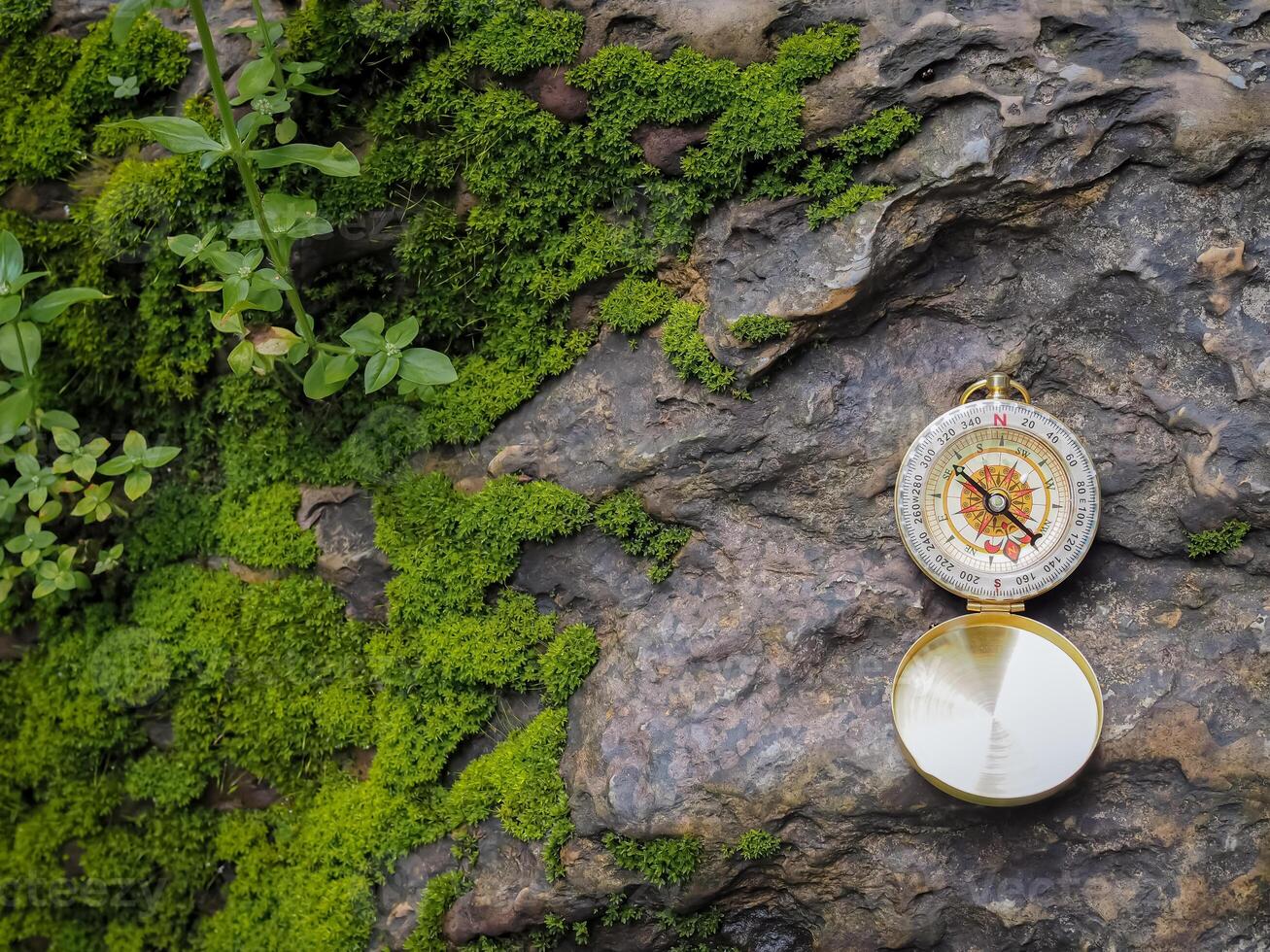 Compass on the rock with green moss background. The concept of world tourism day, Searching the right directions and Travel photo