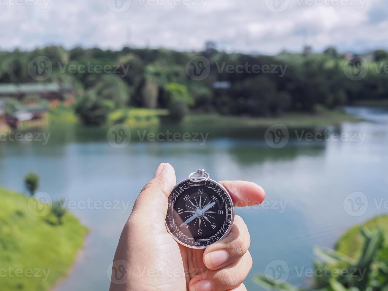 Close up of compass in woman hand with nature as background. The concept of world tourism day, Searching the right directions and Travel photo