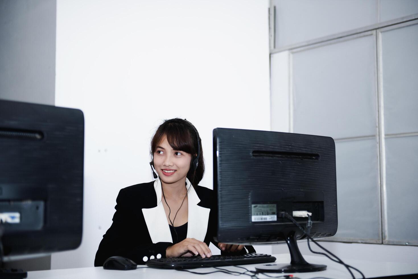 call center smiling business operator customer support team phone services agen working and talking with headset on desktop computer at call center photo