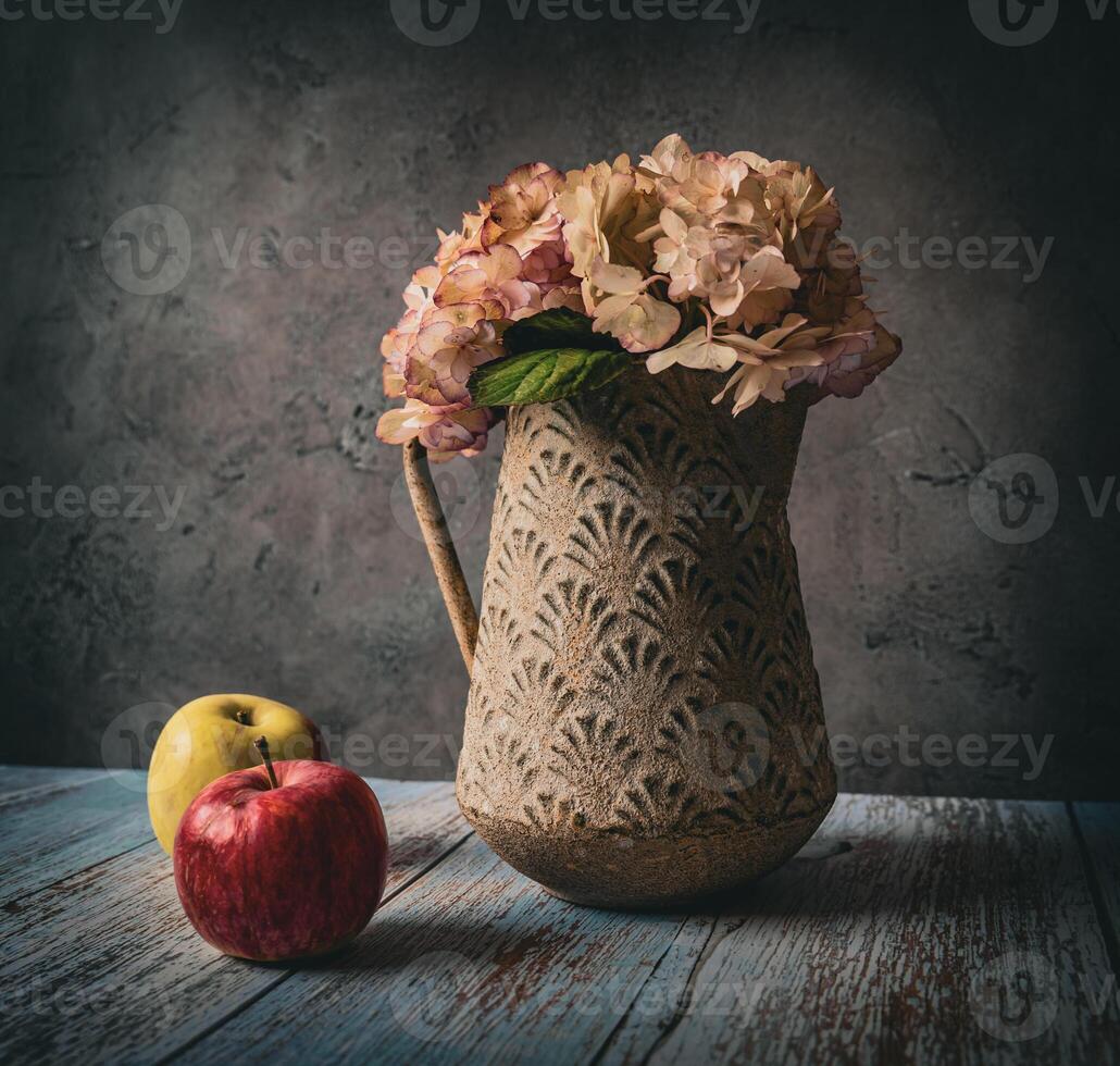Vase with hydrangea flowers and two apples on the table photo