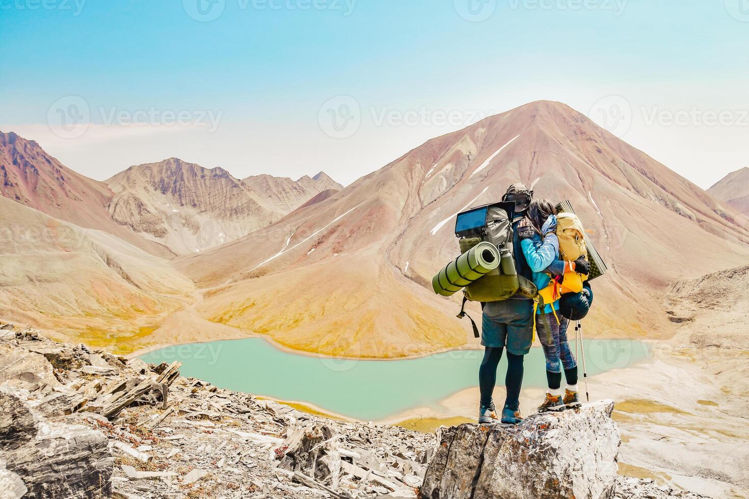 Two caucasian adult hikers together stand hugging caring on top mountain enjoy panorama. Man and woman standing and hugging on the top of the mountain, autumn hike with backpacks.Alpine Kelitsadi lake photo