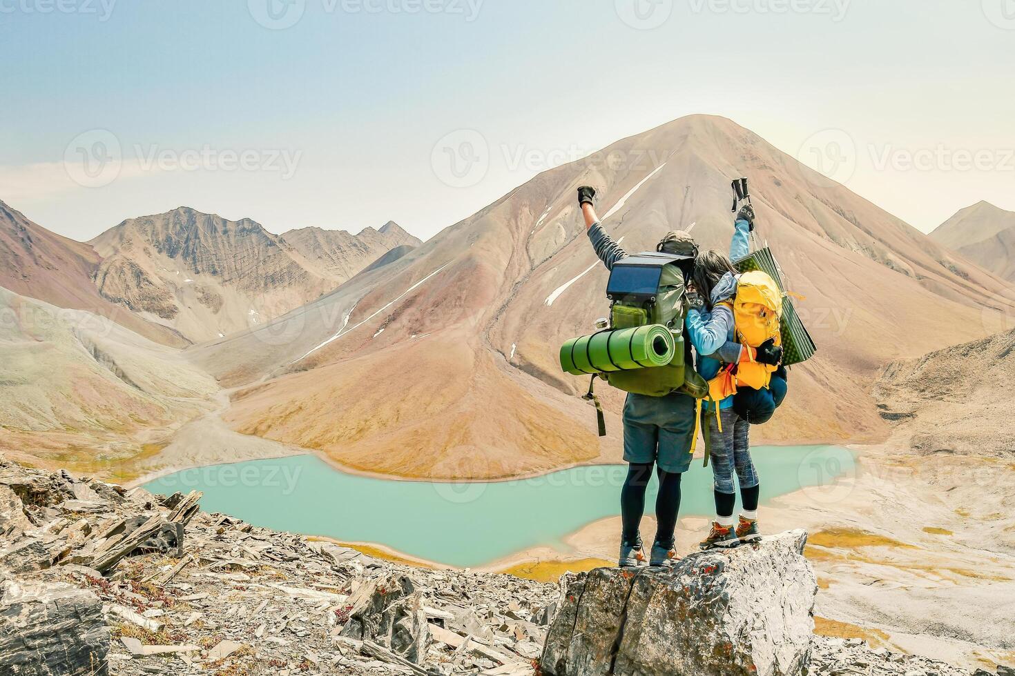 Two caucasian adult hikers together stand hugging caring on top mountain enjoy panorama. Man and woman standing and hugging on the top of the mountain, autumn hike with backpacks.Alpine Kelitsadi lake photo