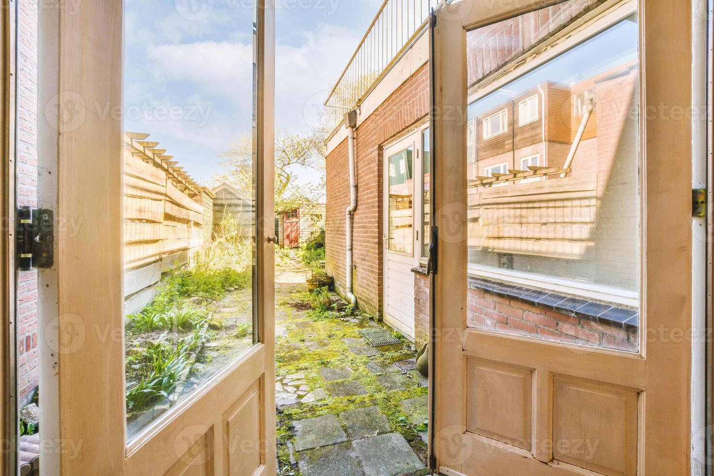 A door with a view of a garden and a brick path photo