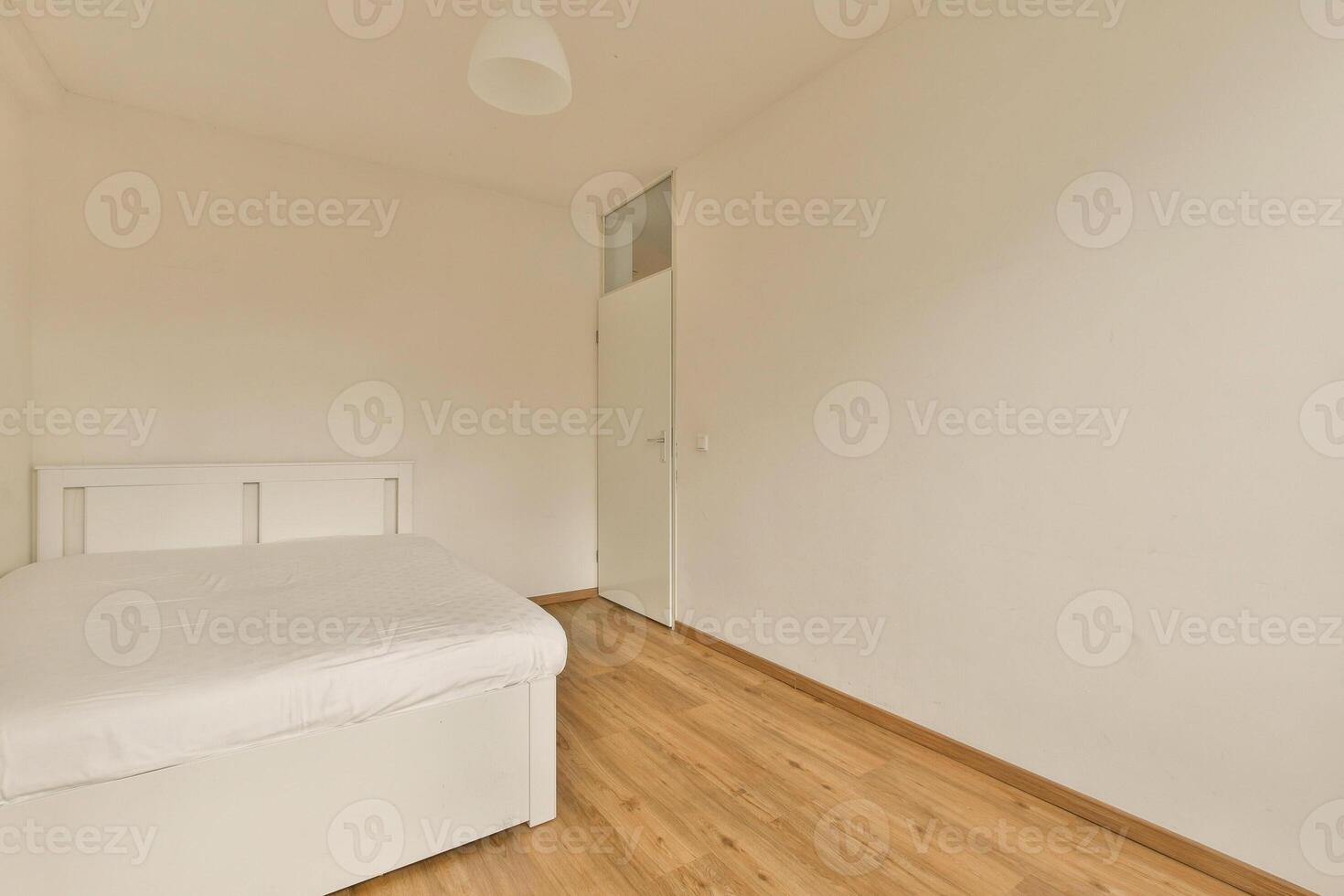 A small bedroom with a white bed and wooden floor photo