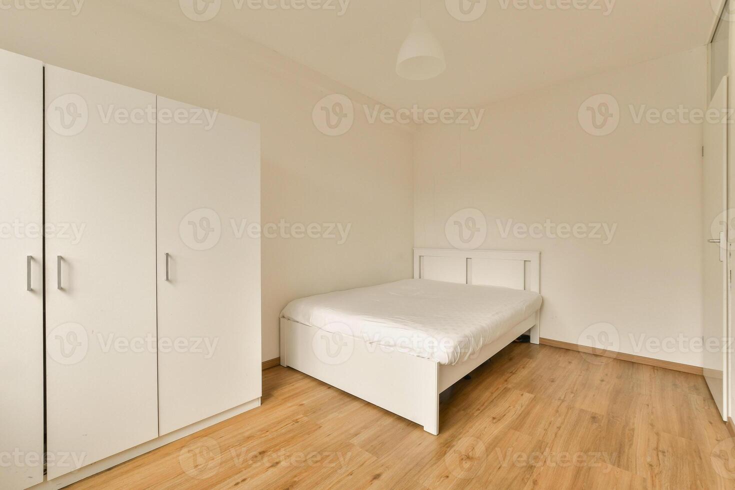 A bedroom with a bed, wardrobe and cupboards photo