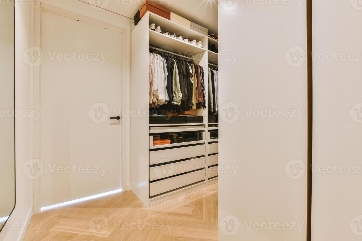 A walk in closet with a wooden floor and white walls photo