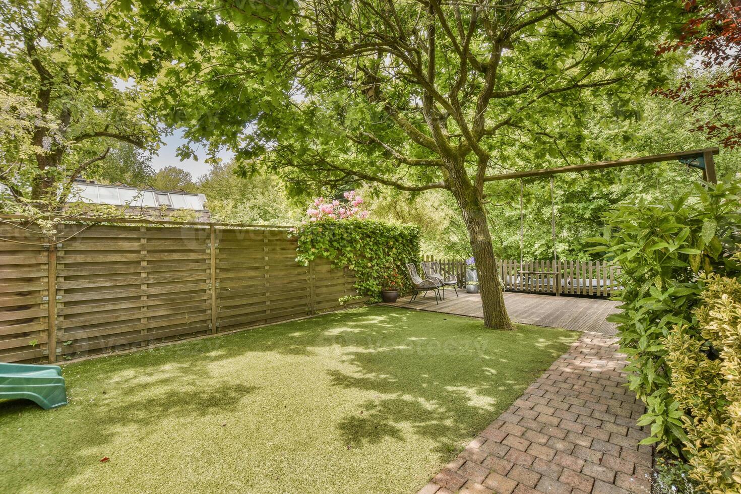 A backyard with a green grass area and a wooden fence photo
