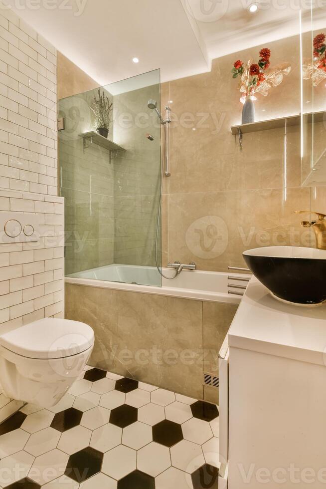 A bathroom with a white toilet, a black and white tile floor, and a glass shower photo