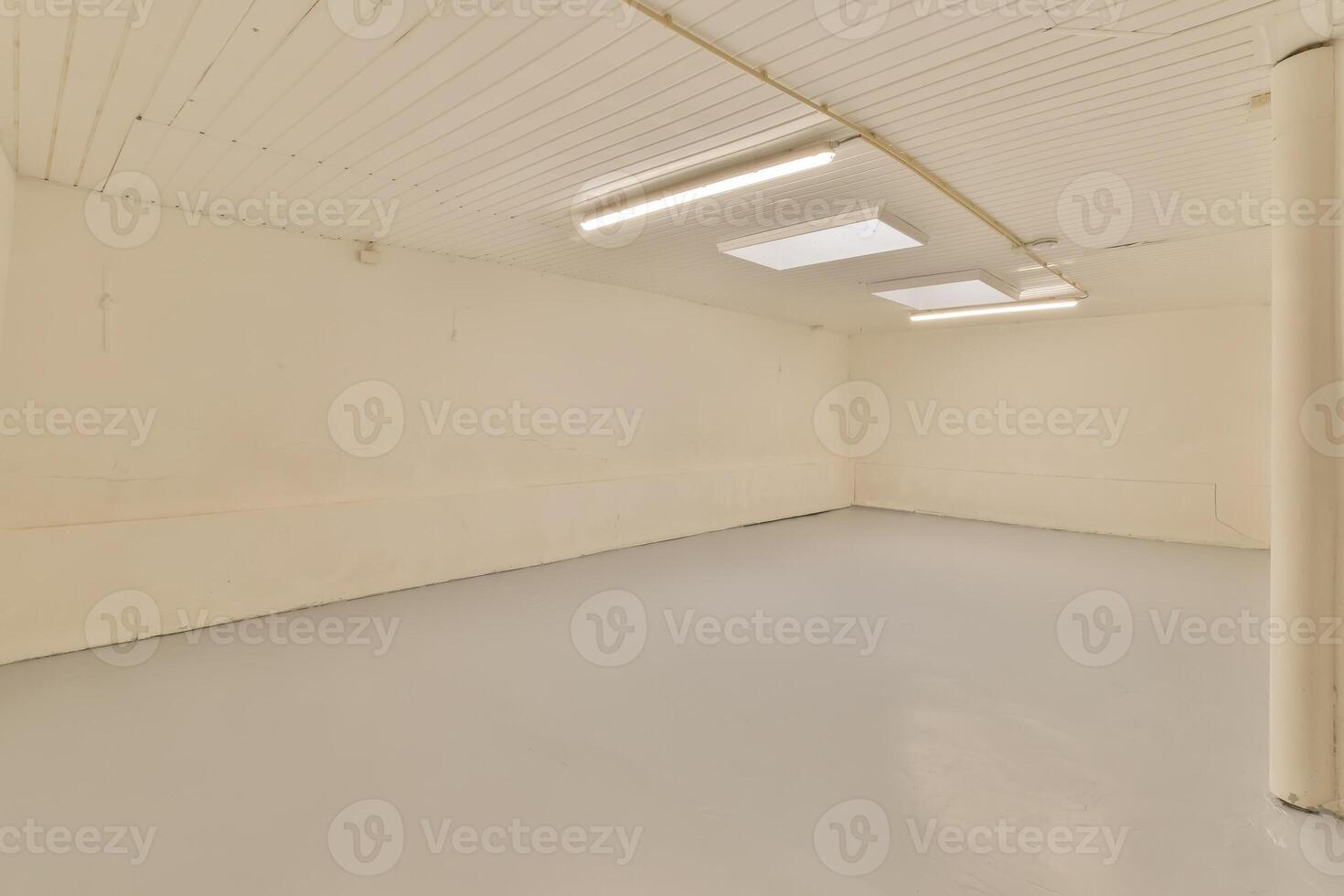An empty room with a white ceiling and a light photo