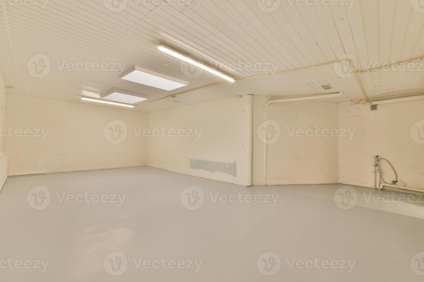 An empty room with a white ceiling and a light photo