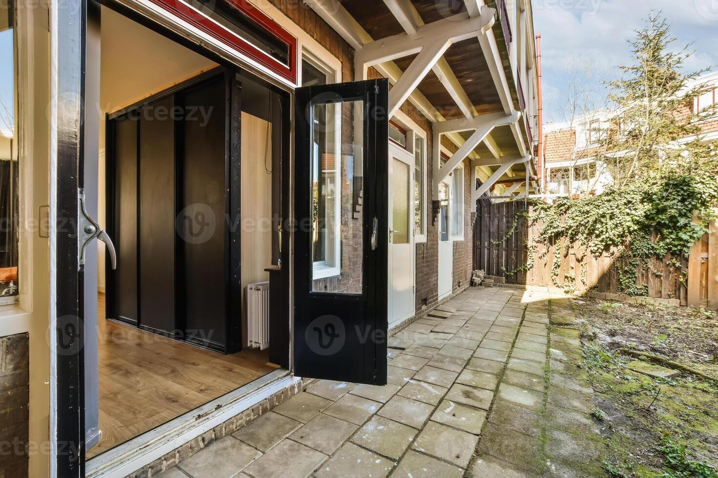 A black door opens to a patio area with a wooden floor photo