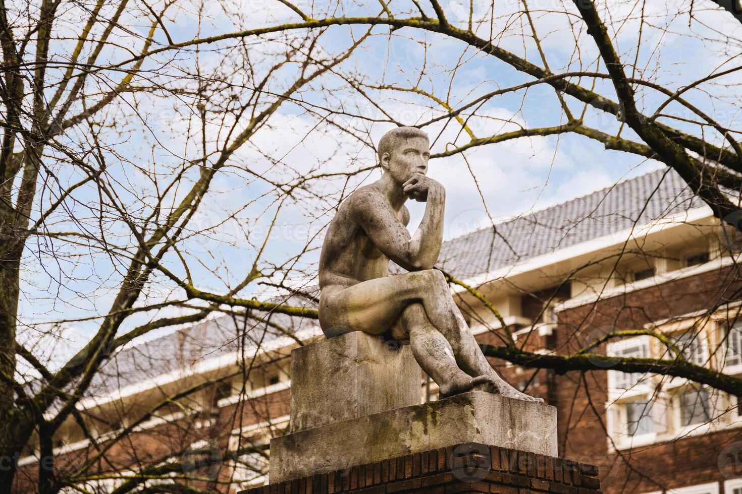 A statue of a man sitting on a brick wall photo