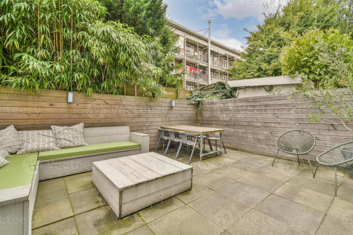 A patio with a green couch and wooden furniture photo