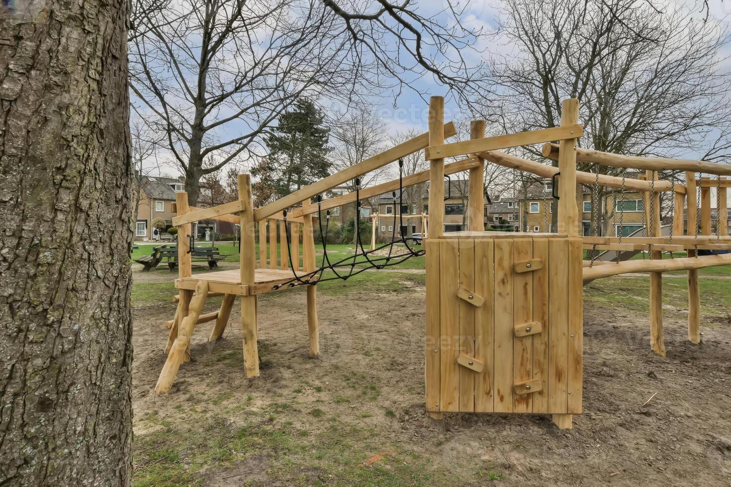 A wooden playground structure with a tree in the background photo